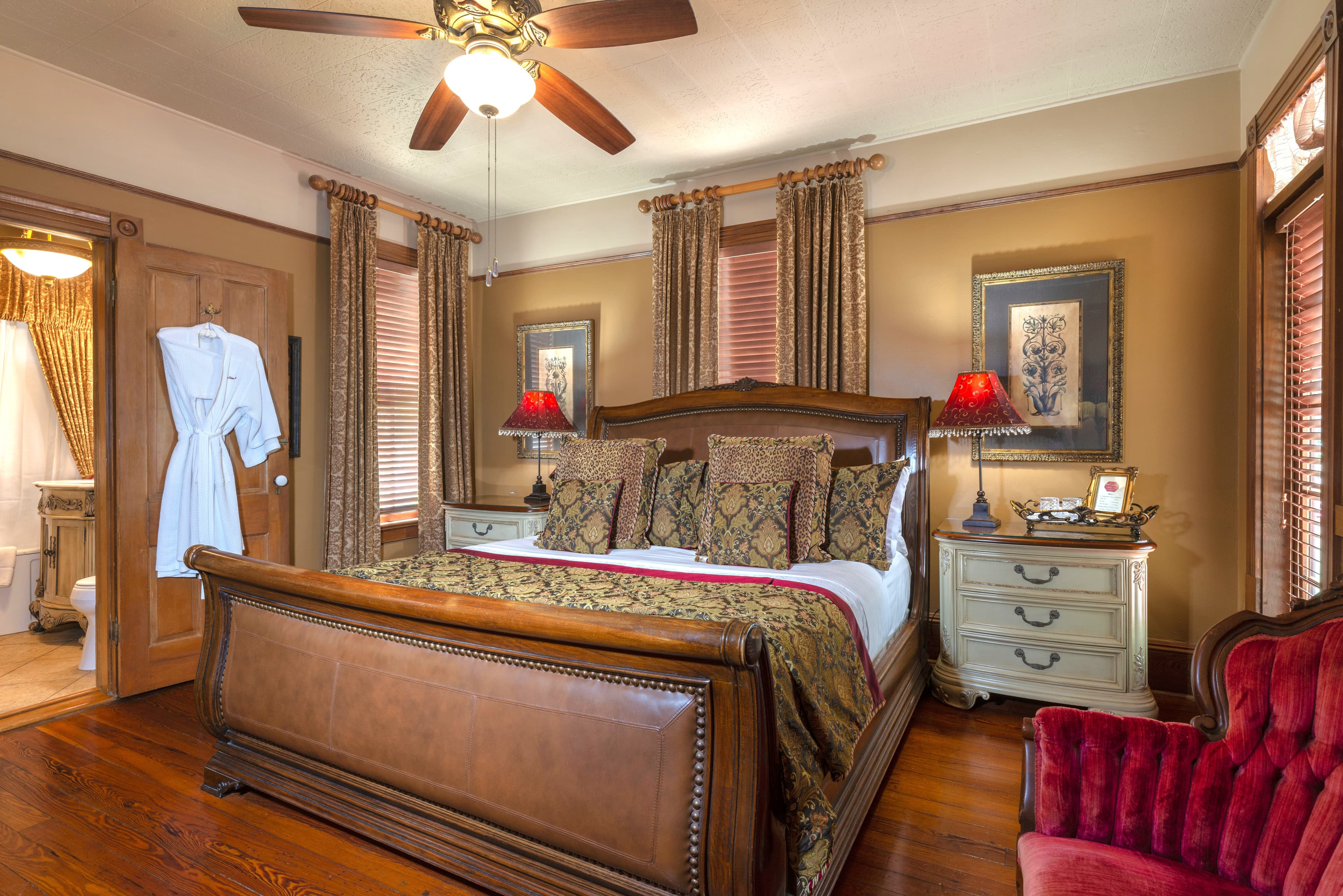 Cozy bedroom featuring a wooden bed with ornate bedding, a vintage armchair, and elegant decor.