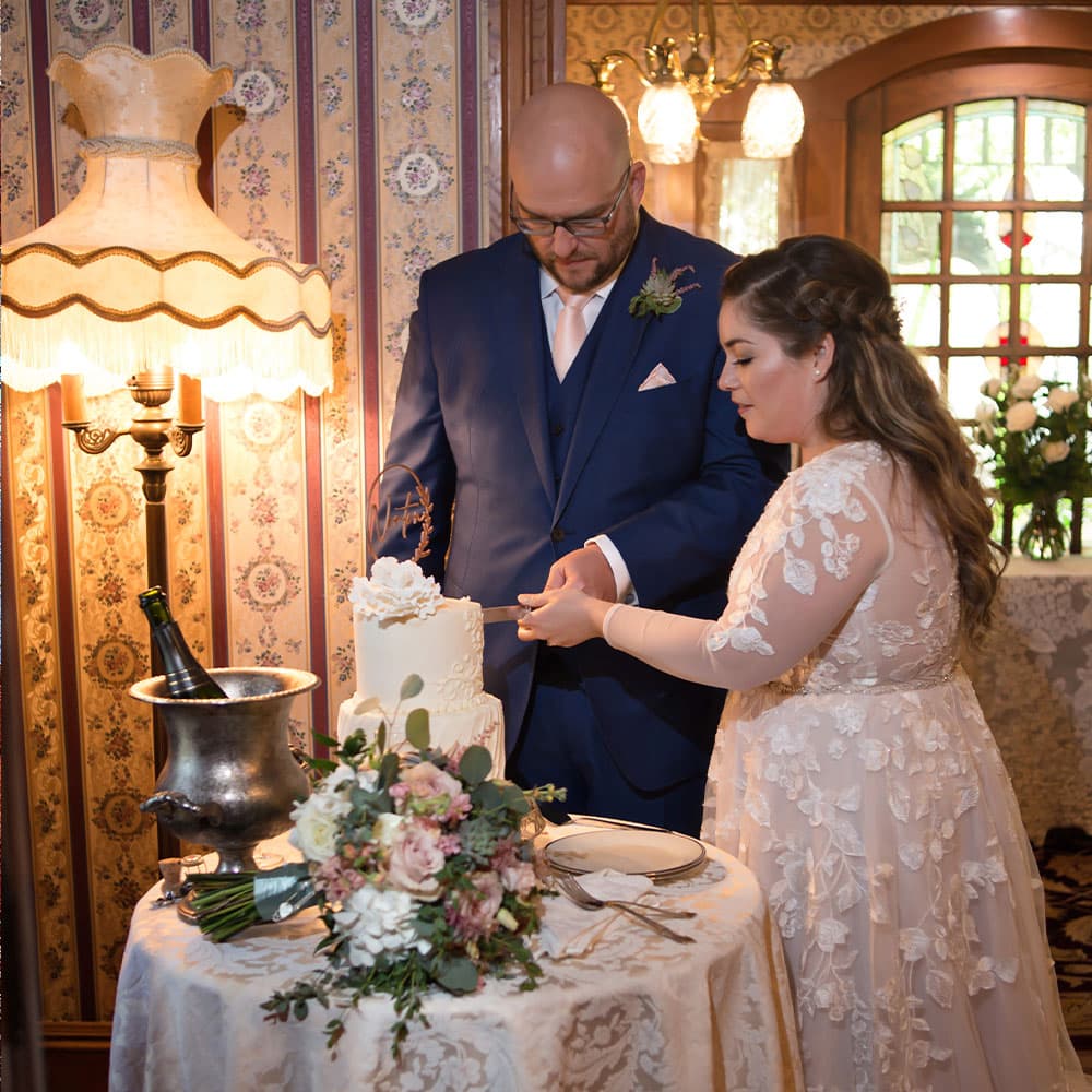 A couple cuts their wedding cake in a beautifully decorated setting.