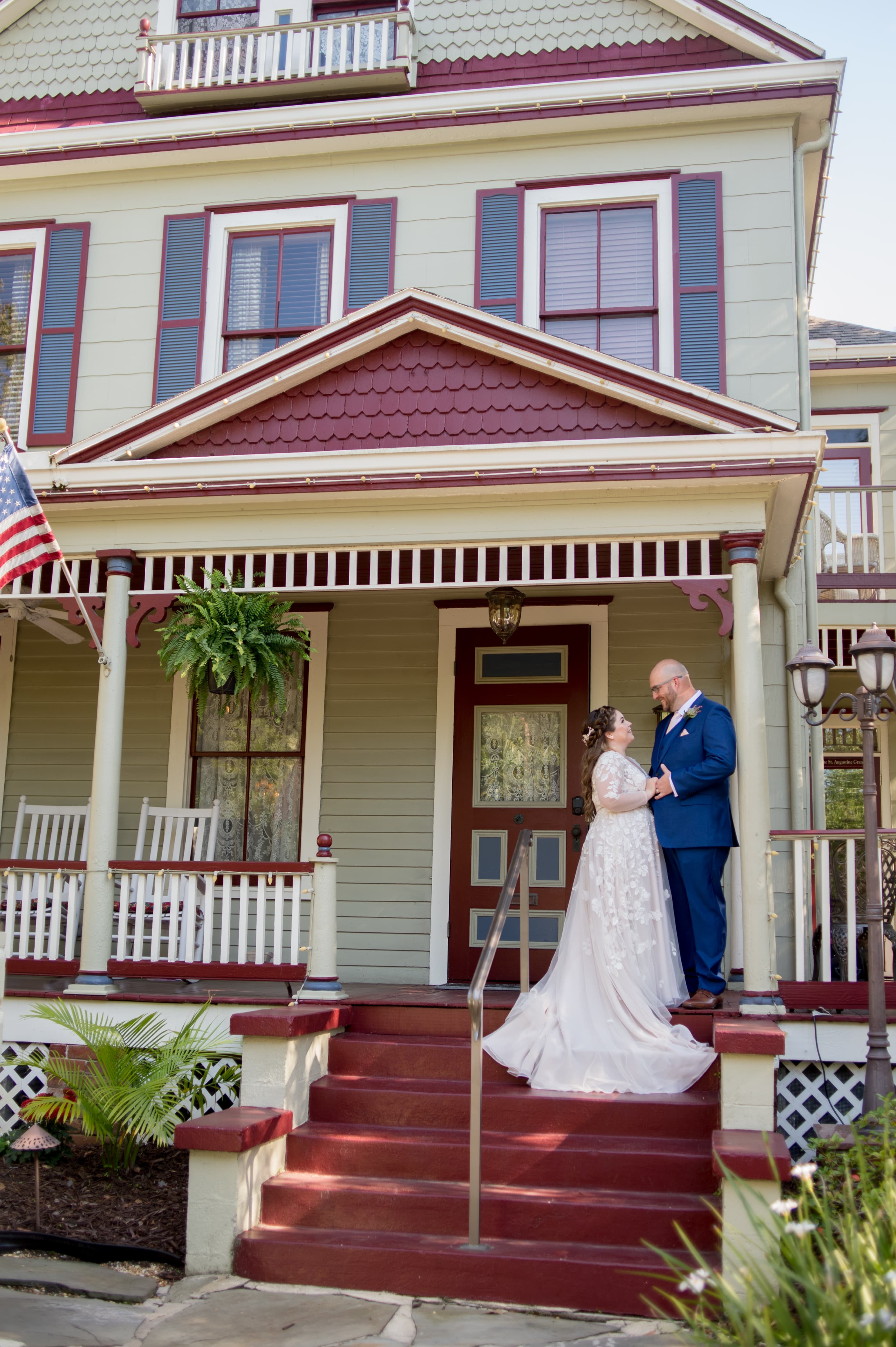 A newlywed couple shares a tender moment on the steps of a charming vintage house.