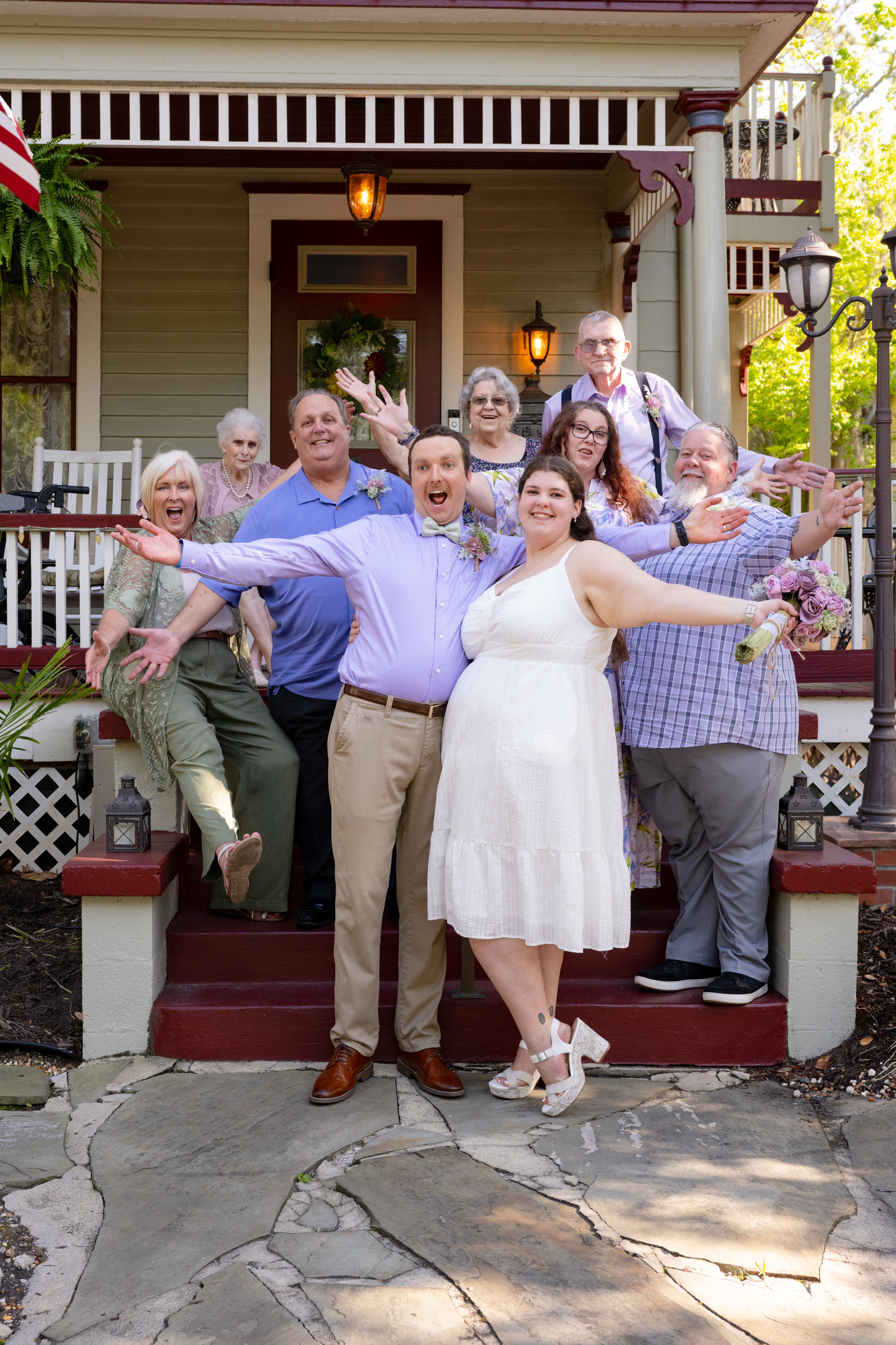 A joyful group of people celebrates together on the steps of a charming house.