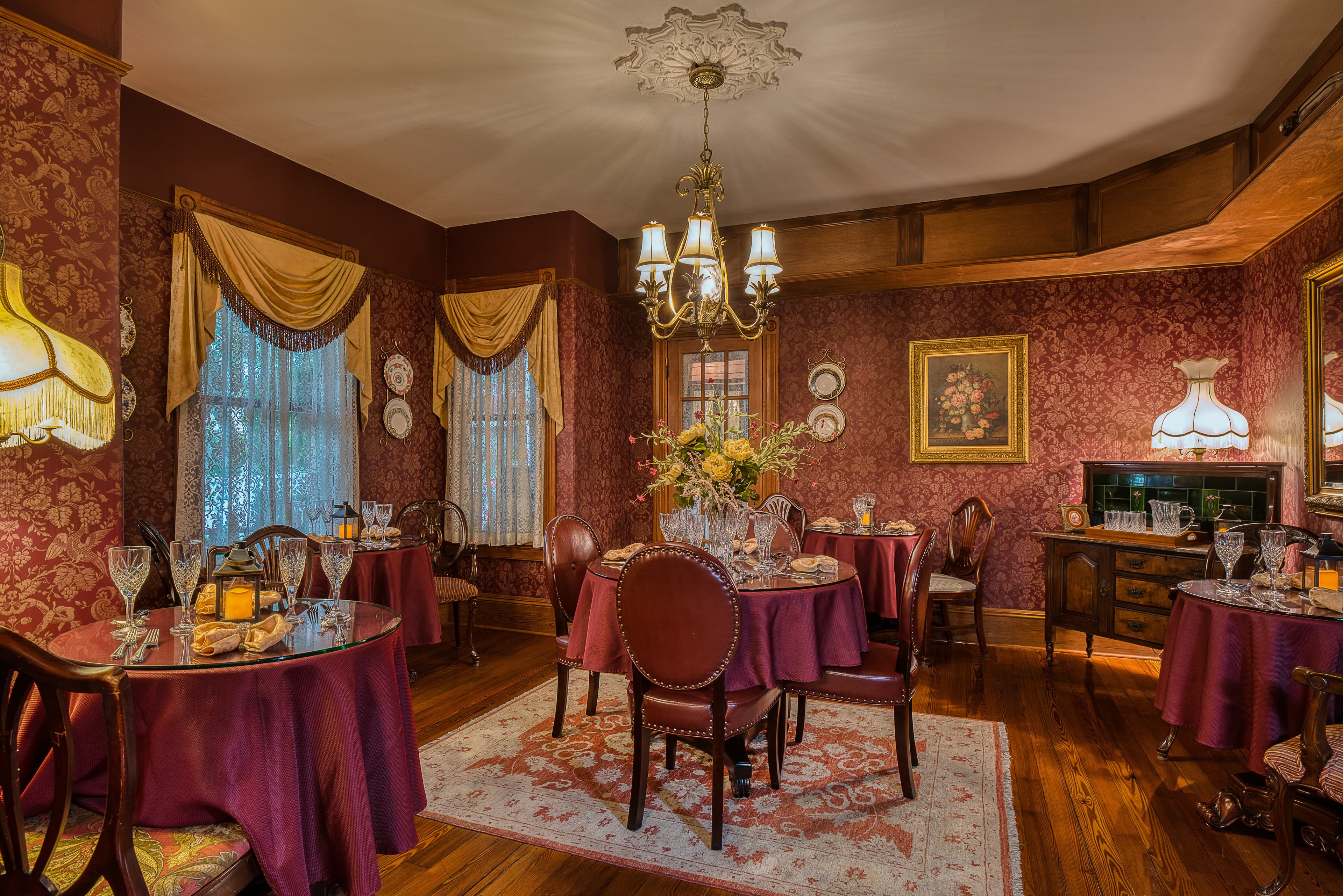 A beautifully arranged dining room with elegant tables, vintage decor, and lush floral arrangements.