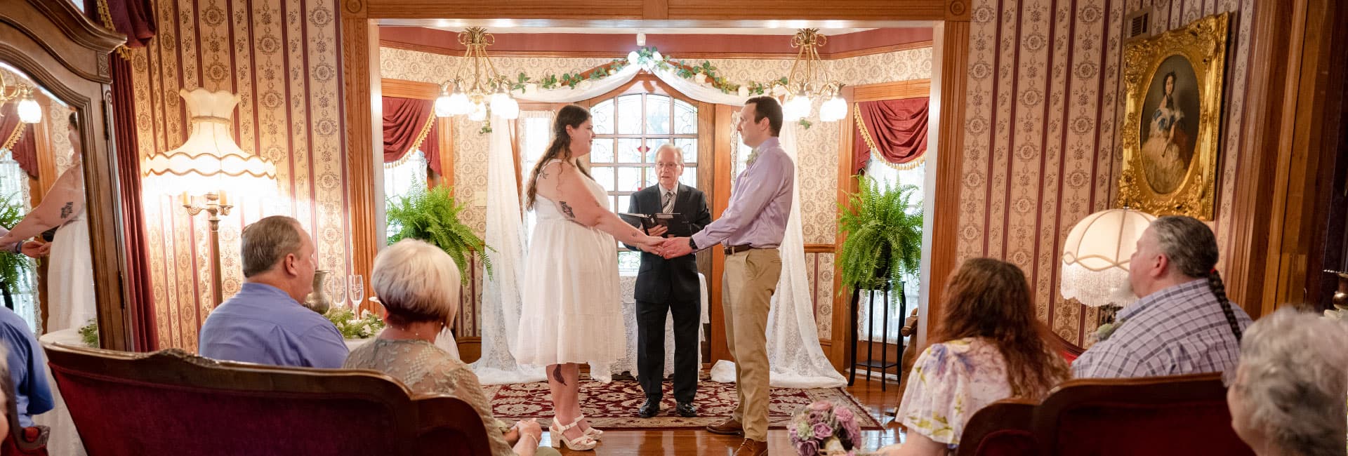 A couple exchanges vows during their wedding ceremony in an elegantly decorated indoor setting.