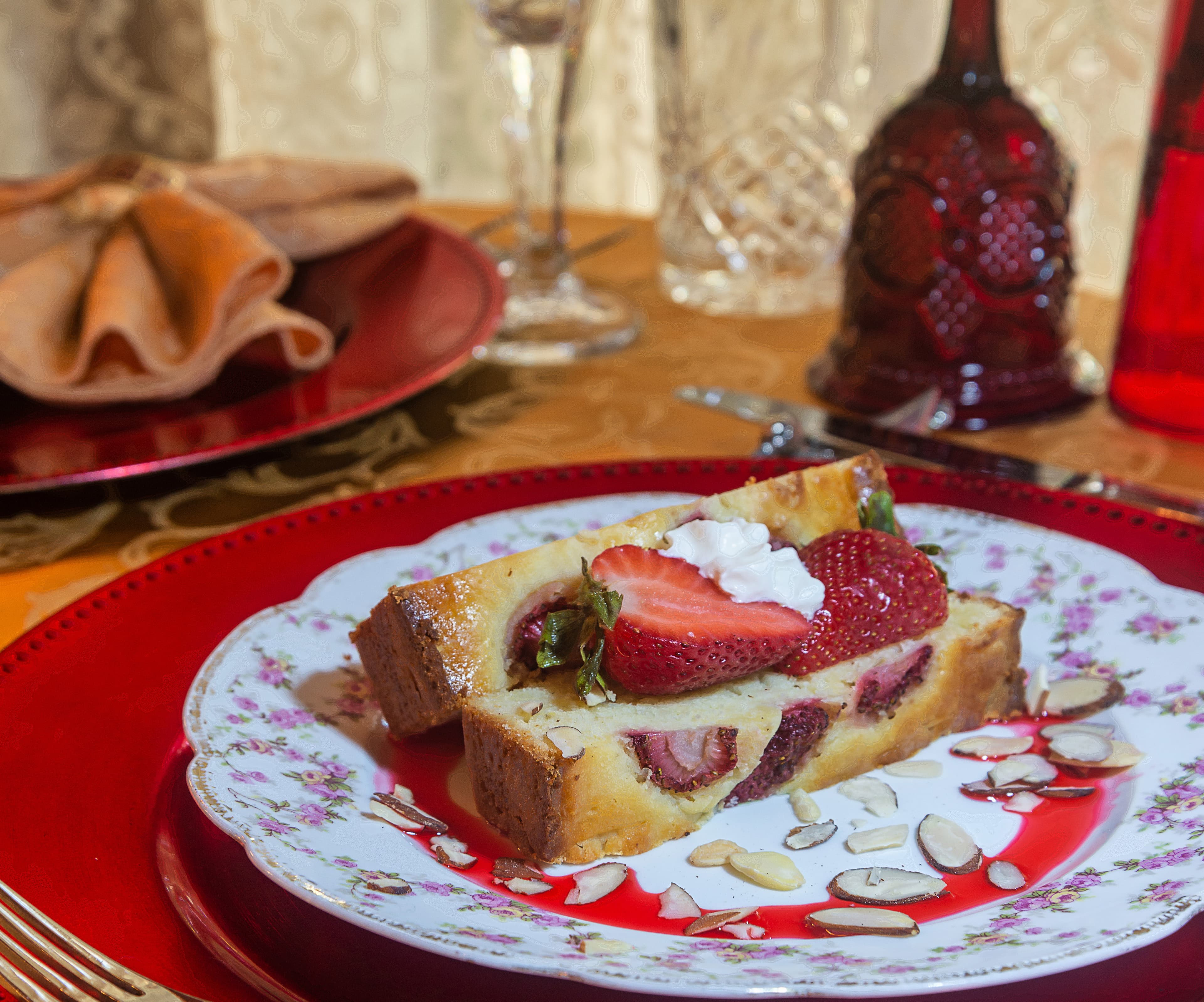 A slice of dessert garnished with strawberries and almonds on a decorative plate.