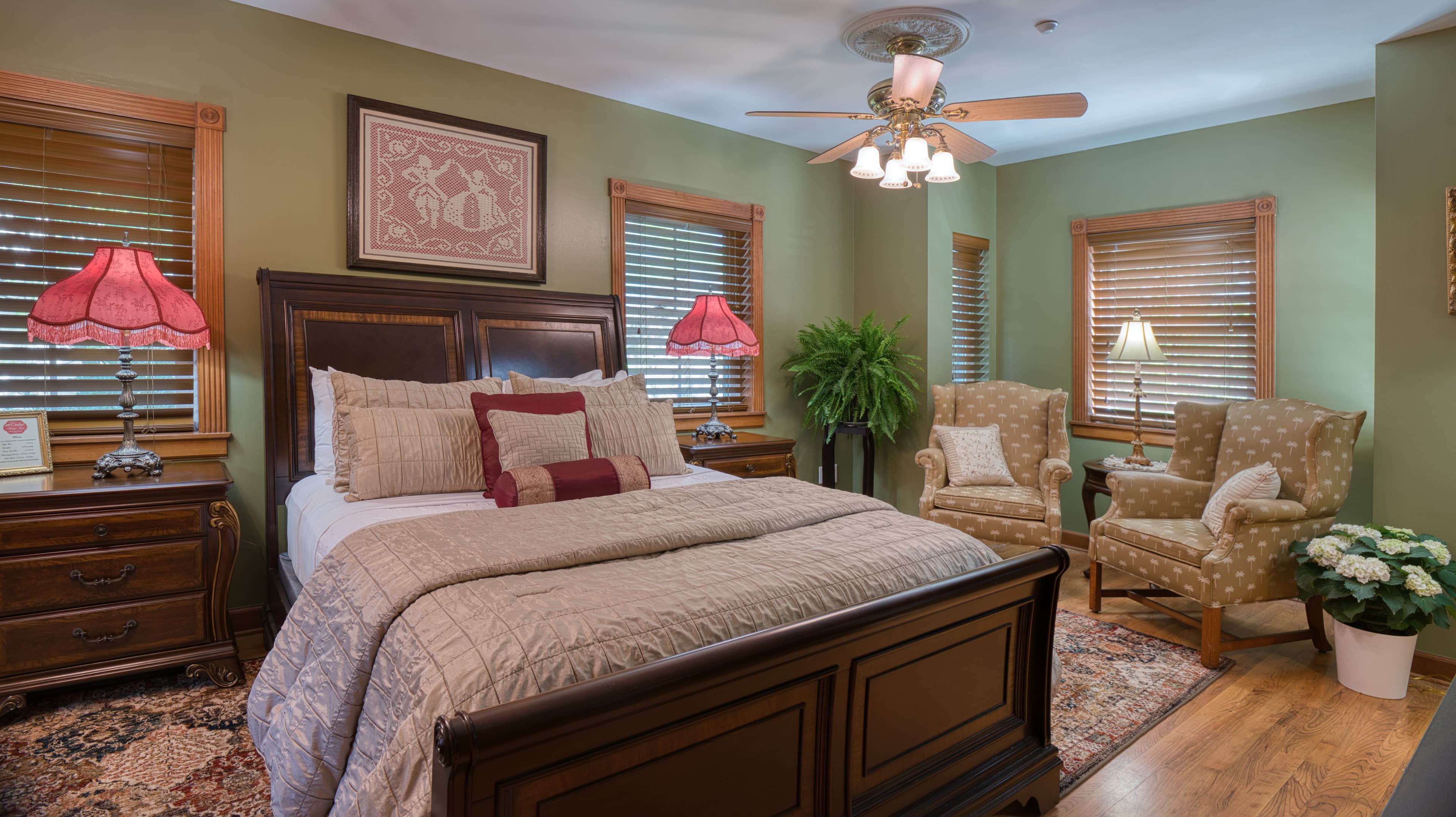 Cozy bedroom with a wooden bed, decorative pillows, lamps, and comfy chairs.