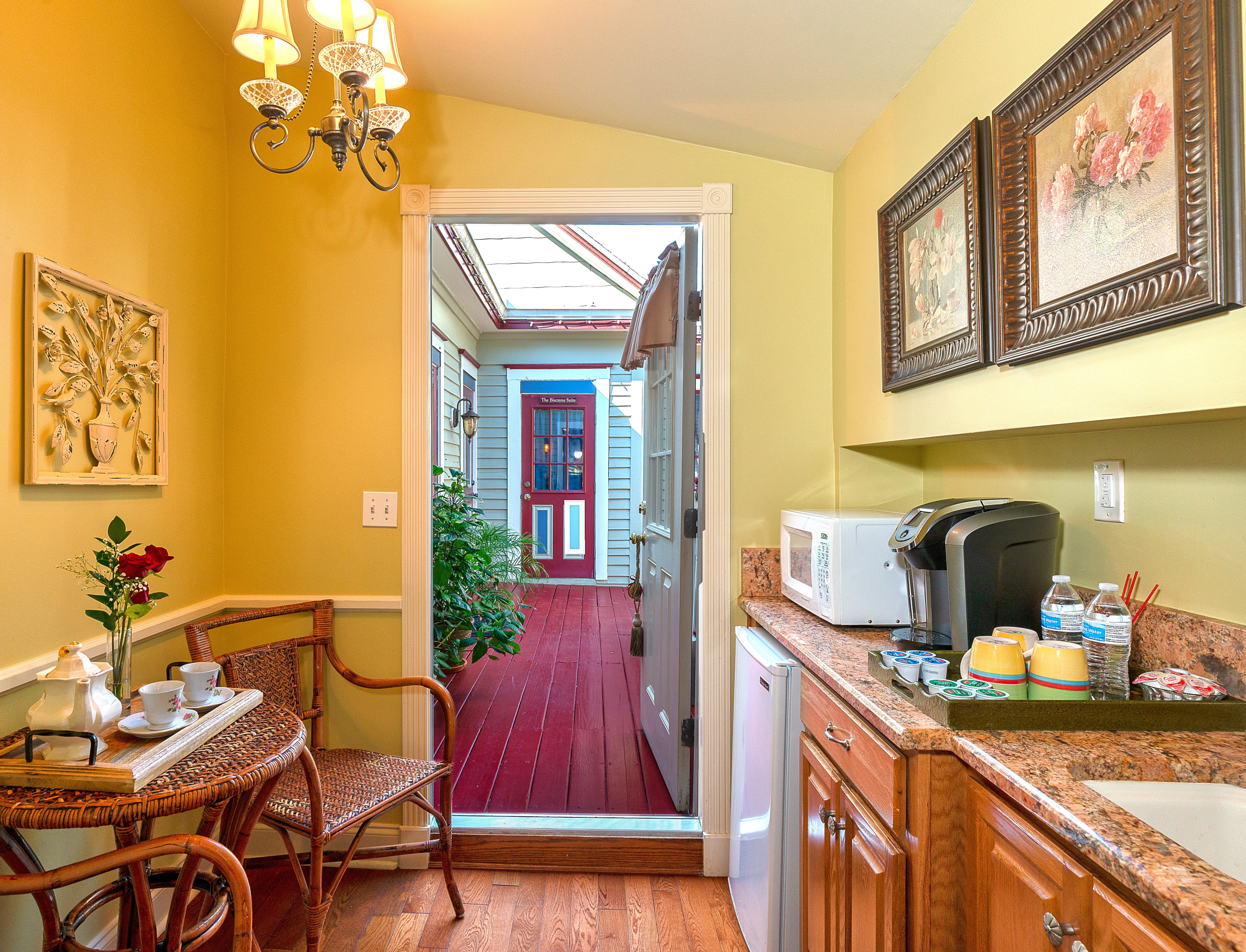 A small dining area with a round table and two chairs, leading to a kitchen with a microwave and a coffee maker.