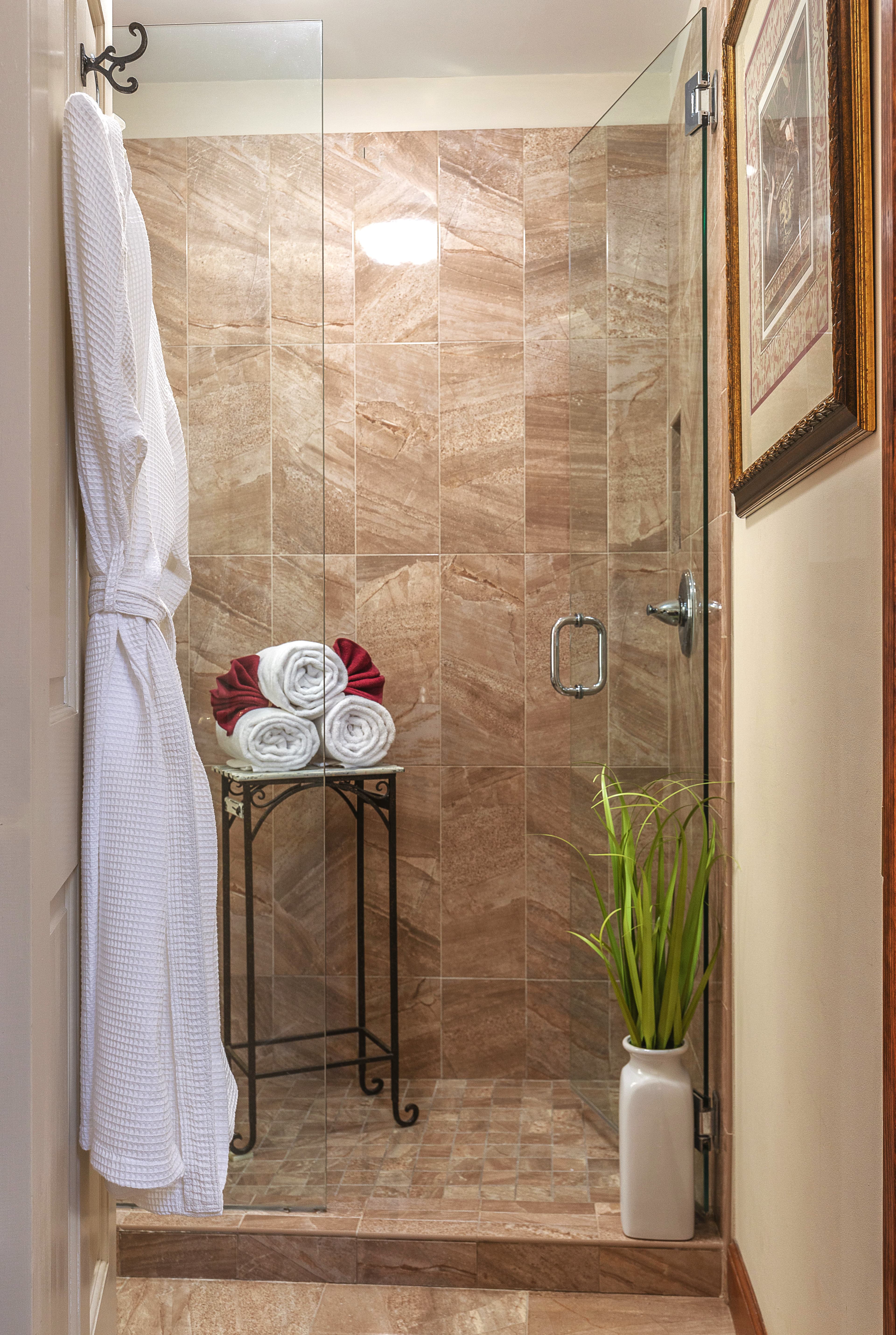 A luxe shower with a glass door, a tiled wall, and a chrome shower head.