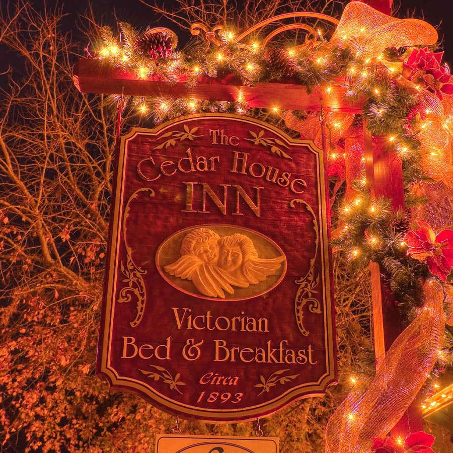 A brightly lit sign for The Cedar House Inn, a Victorian bed and breakfast established in 1893.