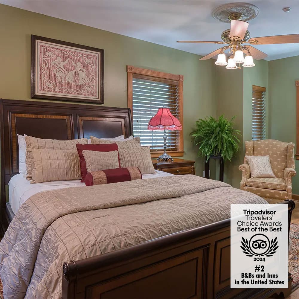 A cozy, elegantly decorated bedroom featuring a large bed, vintage lamp, and green walls.