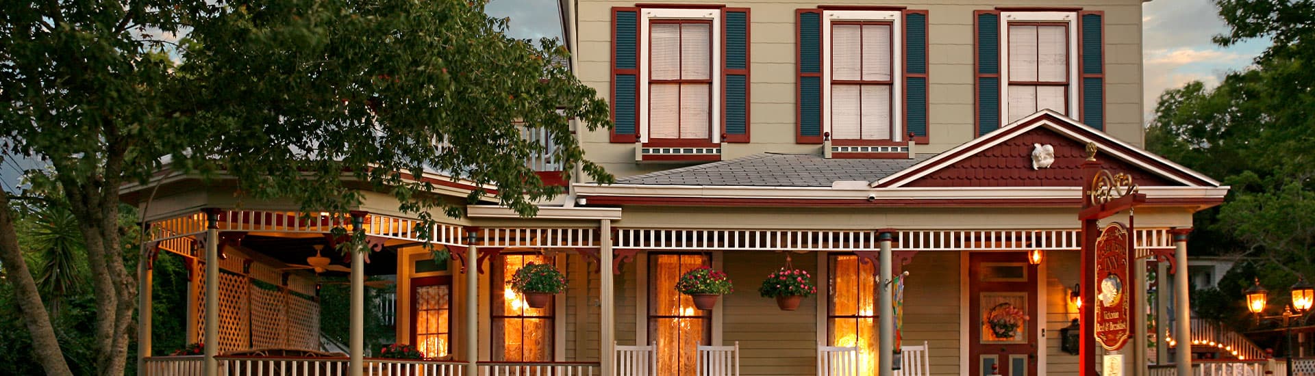 Charming Victorian-style inn with a wraparound porch and lush greenery.